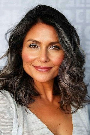 Peinado con ondas y raya a un lado para mujeres mayores de 50 años con caras redondas.