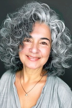 Peinado con rizos grises voluminosos para mujeres mayores de 50 años con caras redondas.